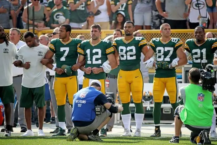 Rodgers #12 with his team during the national anthem