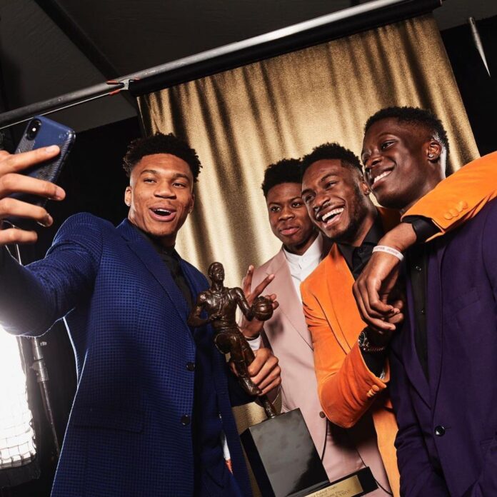 Giannis Holding his 2019 MVP Award while Taking a Selfie with his Brothers